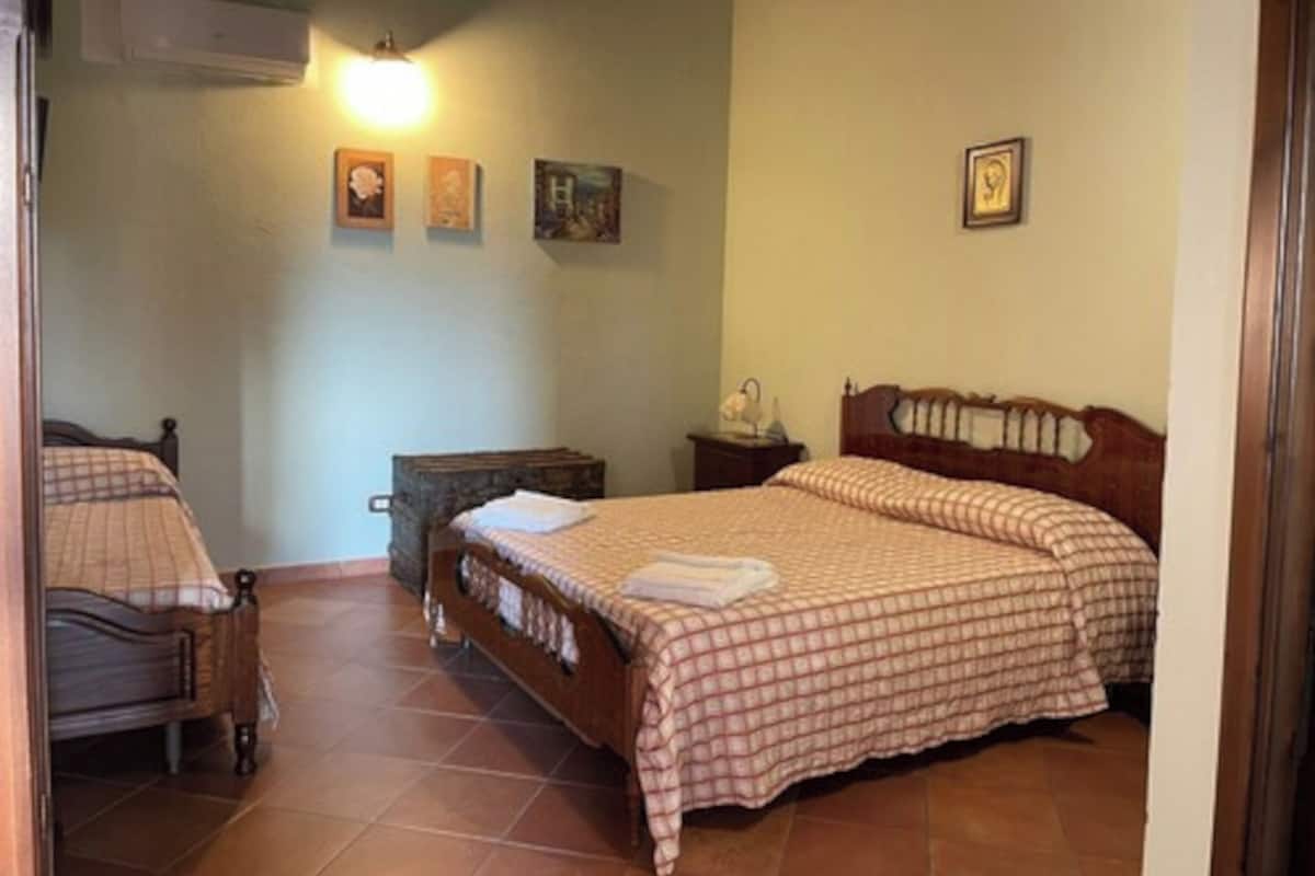 A bedroom with two beds, a nightstand, a dresser, and a wall-mounted air conditioner.