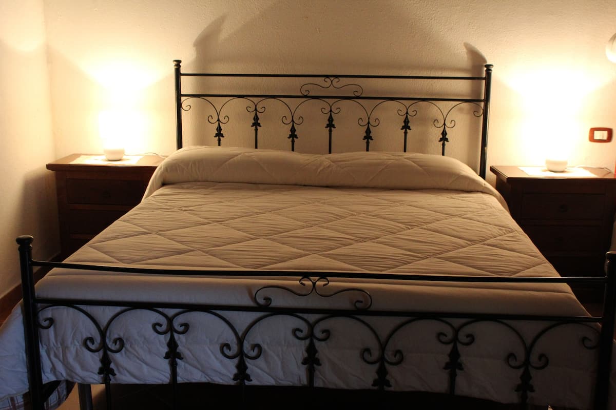 A bed with a quilted mattress and a metal frame, flanked by two bedside tables with lamps.