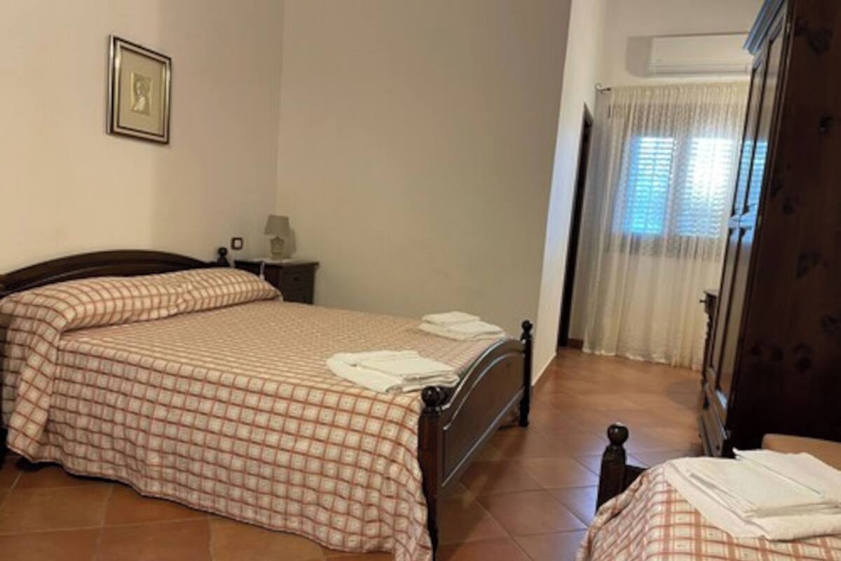 A bedroom with a bed, a nightstand, a lamp, and a window with curtains.