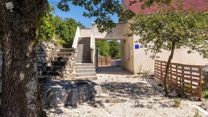 Un escalier en pierre mène à un bâtiment surmonté d’un toit rouge, qui est entouré d’arbres et d’une clôture en bois.
