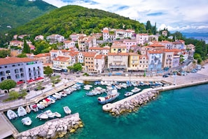 Uma cidade costeira com edifícios coloridos, um porto com barcos e um molhe rochoso.