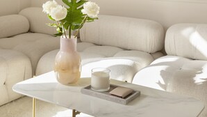 En moderne stue med en hvid sofa, et marmorbord og en vase med blomster.
