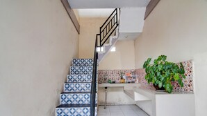A staircase with blue and white patterned tiles leading to a kitchen area with a tiled backsplash and a potted plant. - Hotel O Raya Guest House Syariah (Pekanbaru)