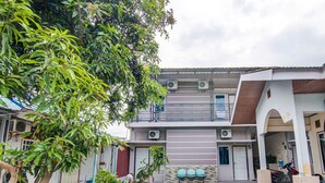 A two-story building with a balcony, air conditioning units, and a paved courtyard. - Hotel O Raya Guest House Syariah (Pekanbaru)