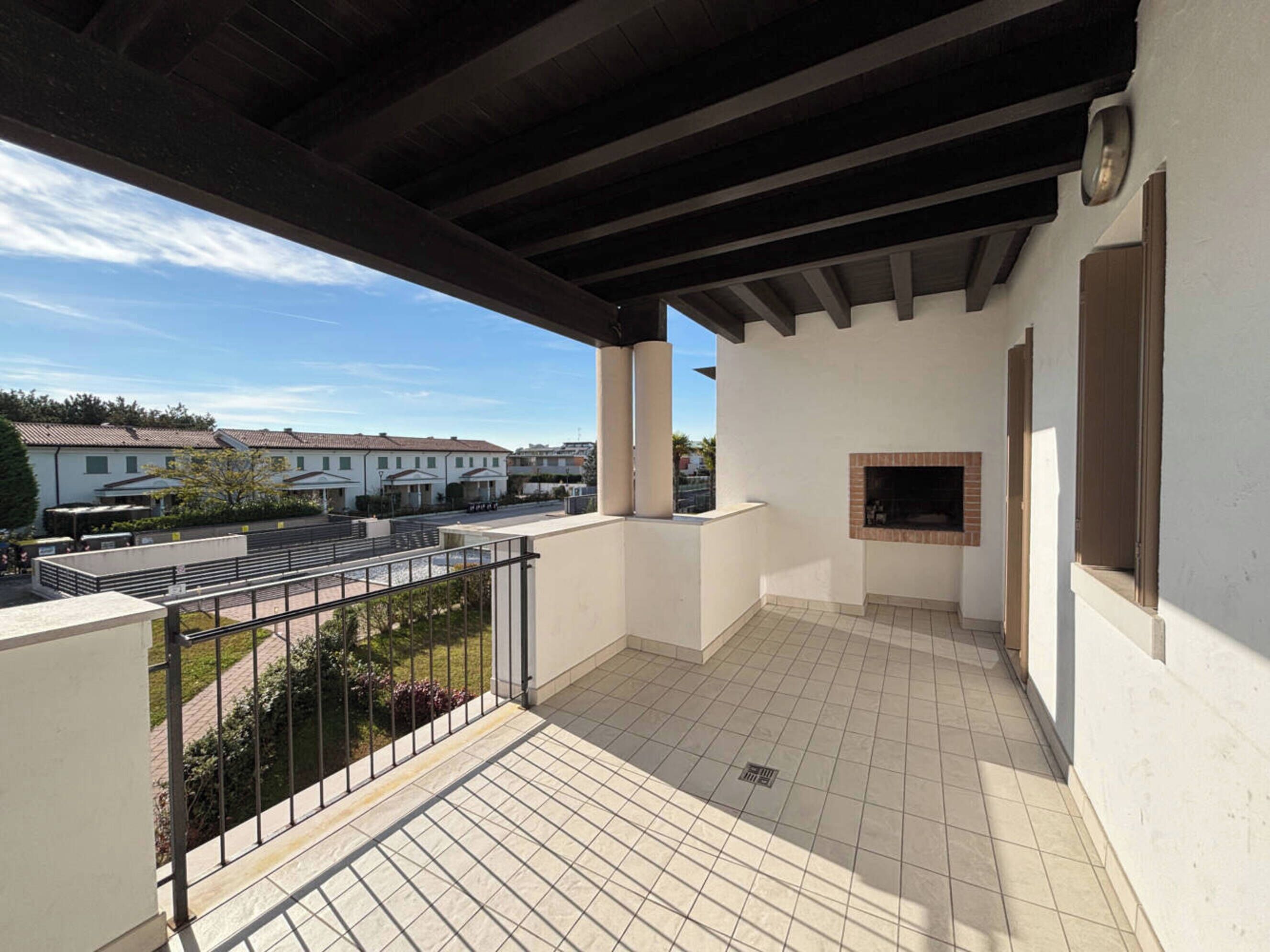 Un balcó amb paviment de rajola, una llar de pedra i vista cap a edificis al fons.
