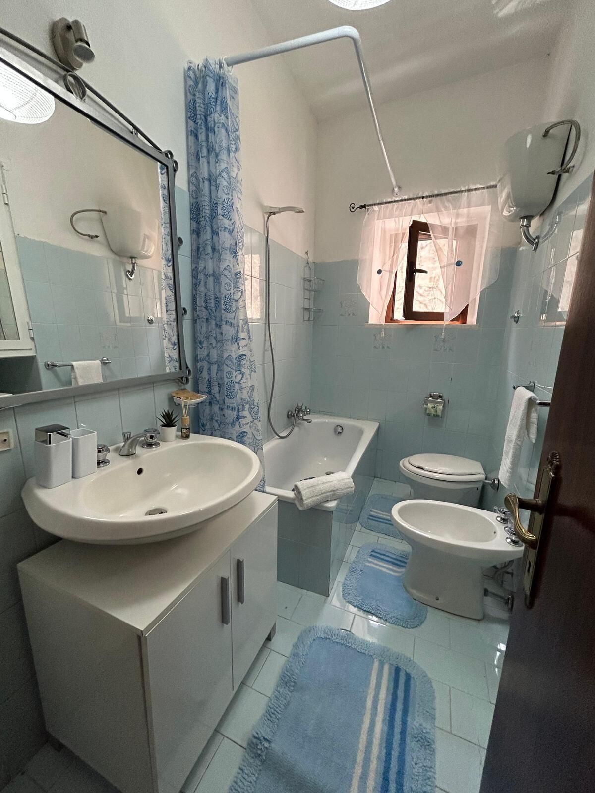 A bathroom with a sink, bathtub, toilet, and bidet.
