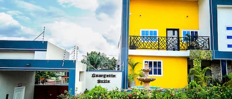 Un immeuble de deux étages avec une façade jaune, un balcon doté d’une balustrade noire et une enseigne indiquant « Georgetown Suites ».