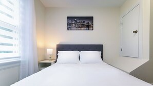 A neatly made bed with white linens, a headboard, and a nightstand with a lamp. - Fully renovated house in Toronto
 (Toronto)