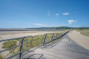 A wooden boardwalk leading to a beach with a metal railing. - Swn Y Mor - 4 Bedroom - Llanelli (Llanelli)