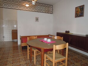 A dining area with a round table, wooden chairs, and a cabinet. - Peaceful Villa With Garden 500mt From the sea (San Michele al Tagliamento)