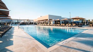 A swimming pool with sun loungers and umbrellas, surrounded by buildings.