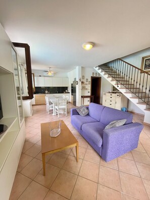 A modern living room with a sofa, coffee table, and a staircase leading to an upper level.