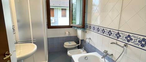 A bathroom with a shower, toilet, bidet, and bathtub.