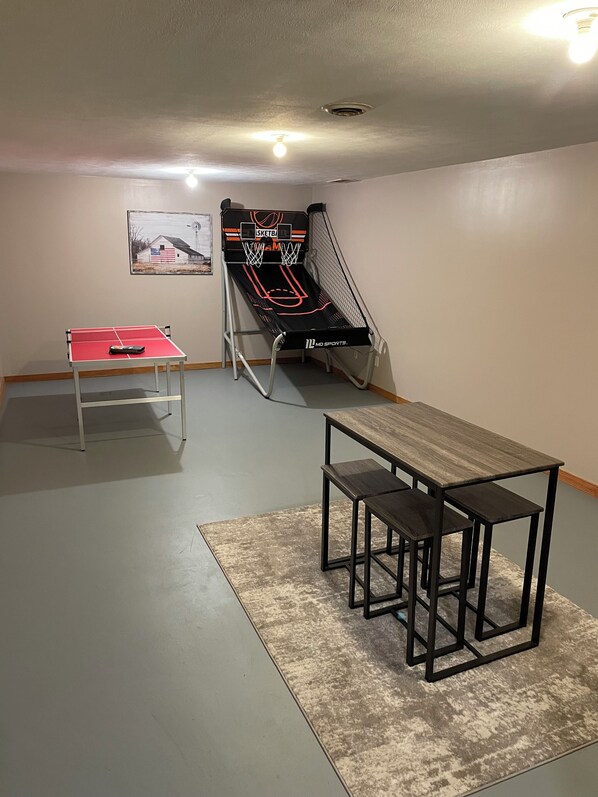 A room with a ping pong table, a small table with benches, and a basketball hoop. - Charming farmhouse in a rural setting with an easy drive to Purdue (Wolcott)