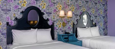 A hotel room with two beds, a large mirror, and a patterned wallpaper.