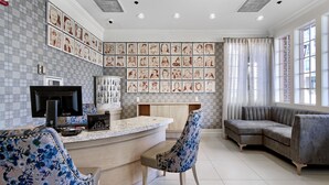 A modern living room with a curved sofa, a bar area with a flat-screen TV, and a wall adorned with framed artwork. - Hotel Fiona (San Francisco)