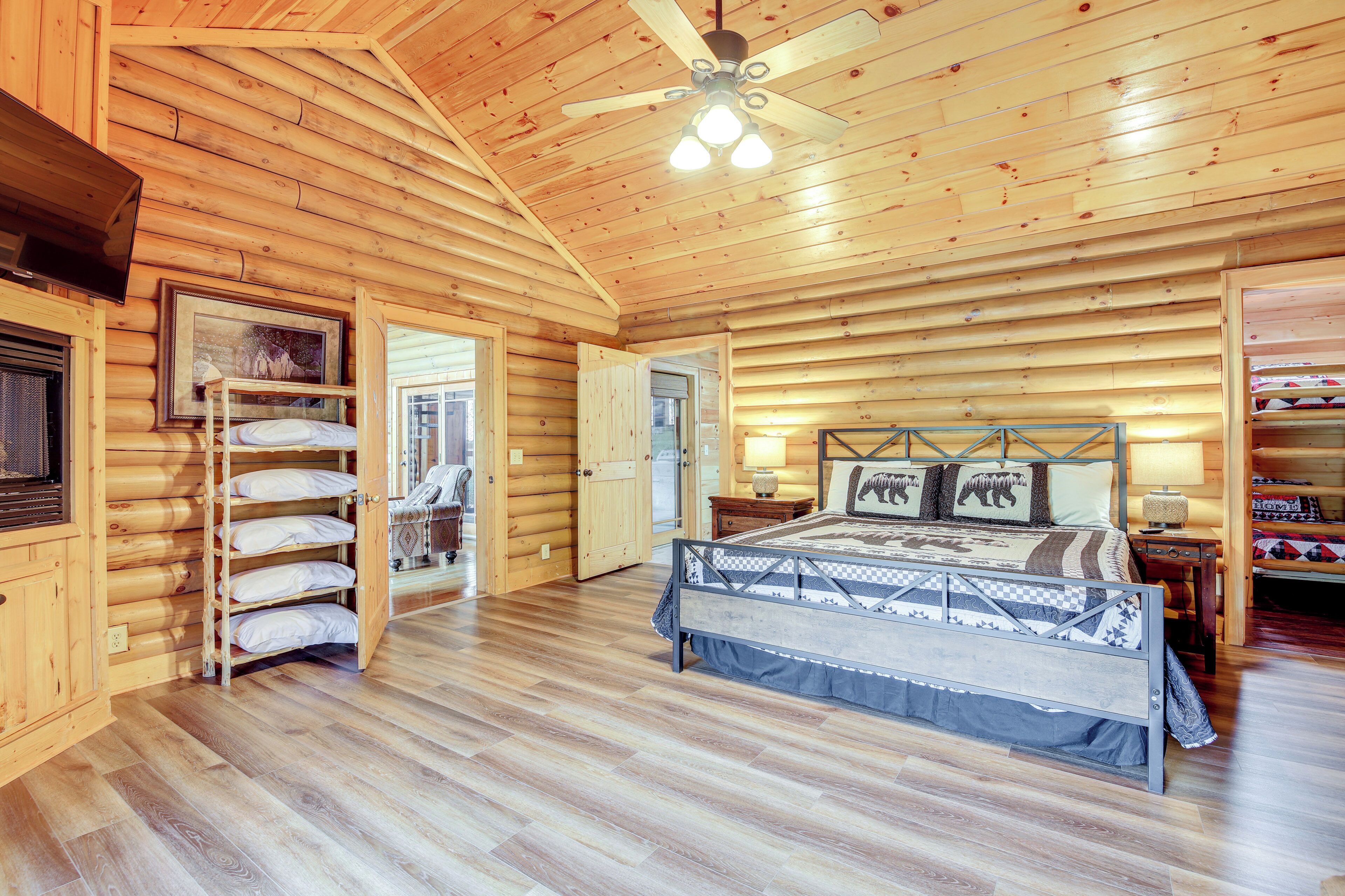 Ein Schlafzimmer in einer Blockhütte mit einem Bett, einem hölzernen Deckenventilator und einem Fenster.