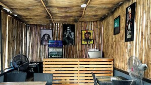 A restaurant with a rustic bamboo ceiling, wooden slats on the walls, and a mix of wicker and metal furniture. - House 2 Guest House (Lagos)