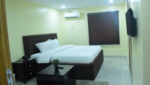 A bedroom with a bed, bedside table, and a small plant. - House 2 Guest House (Lagos)
