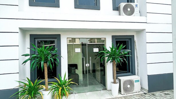 A modern building with a clean facade, large windows, and potted plants at the entrance. - House 2 Guest House (Lagos)