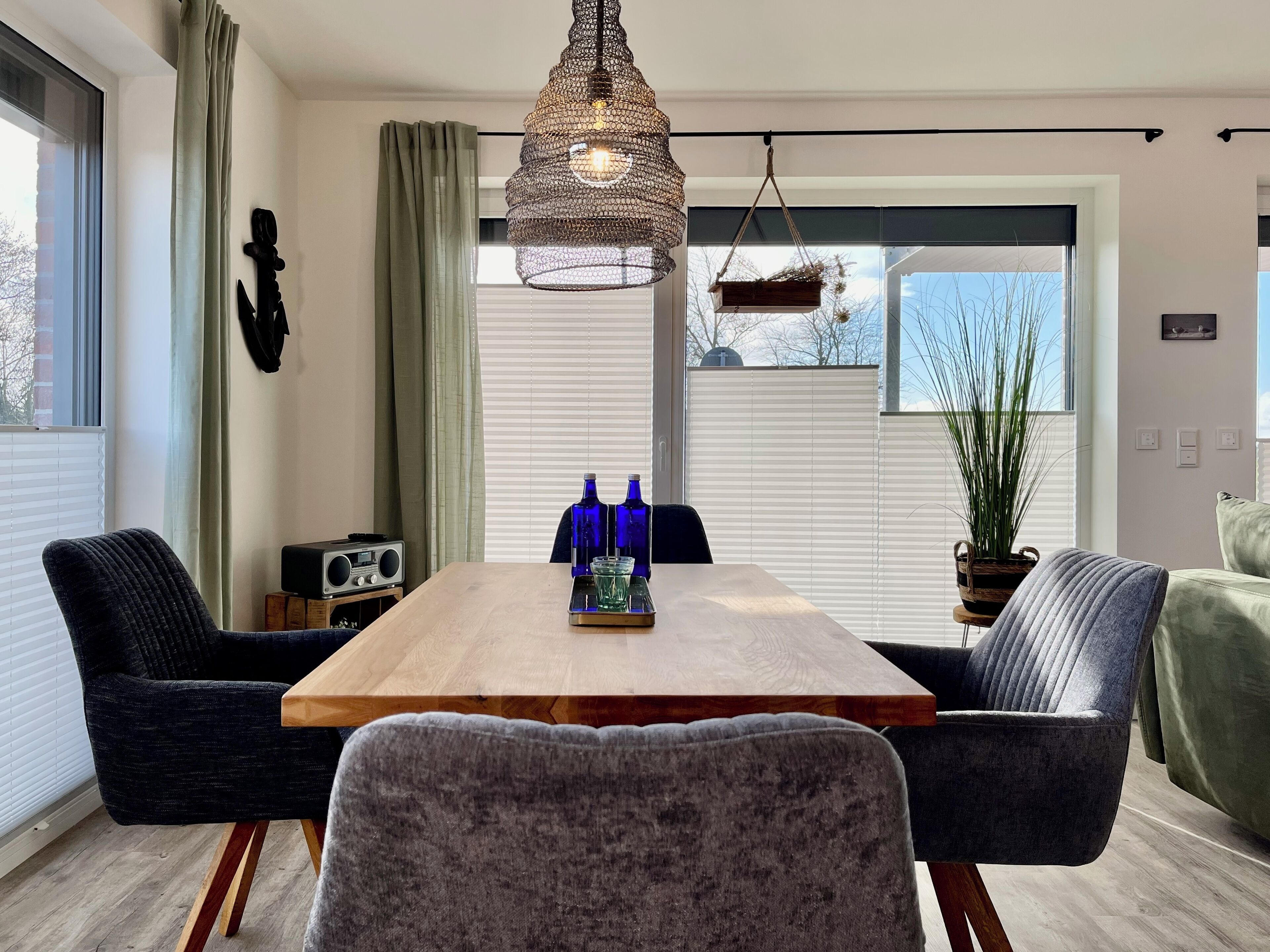 A modern dining area with a wooden table, two black chairs, and a hanging light fixture.