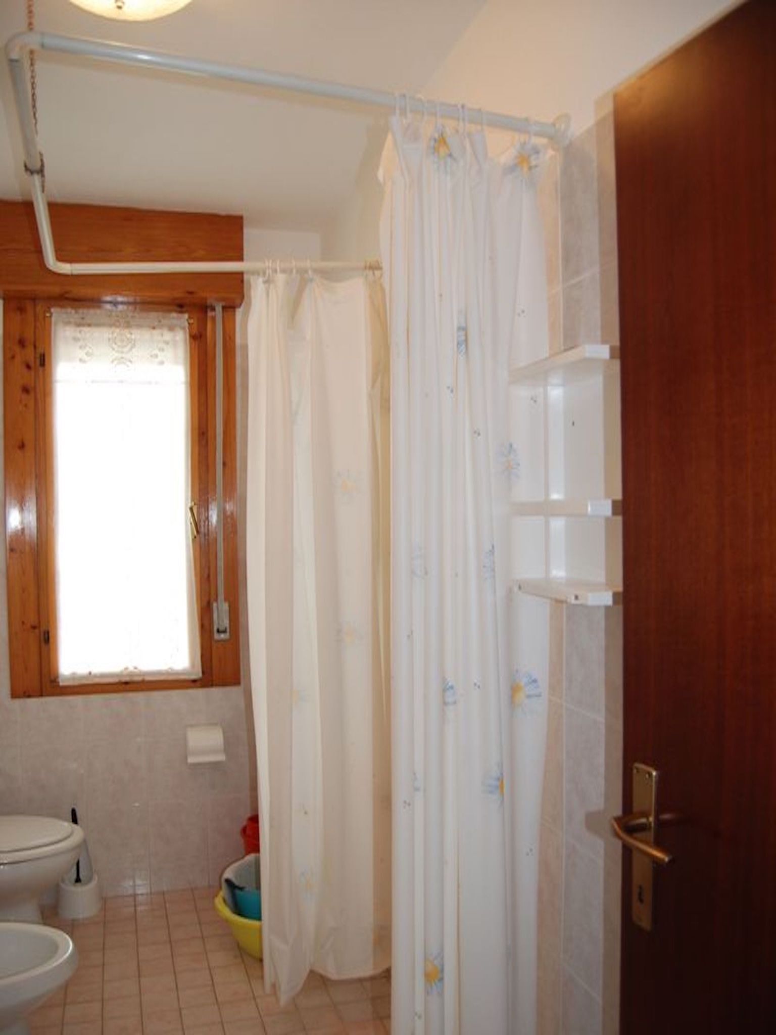 A bathroom with a shower curtain, a toilet, and a window.