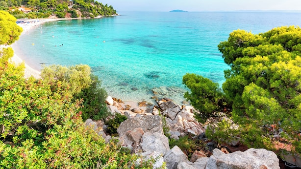 Un paysage côtier caractérisé par une eau turquoise et limpide, une côte rocheuse et une végétation verdoyante et luxuriante.