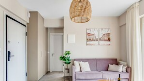 Un salon moderne avec un canapé, une table basse sur laquelle se trouvent de la nourriture et des boissons, un luminaire suspendu et une porte.