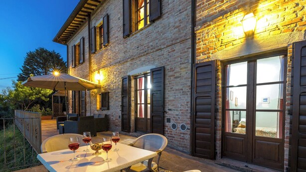 An outdoor patio with a table set for dining, featuring wine glasses and a bowl of fruit. - Casa Eusebia 8+2, Emma VIllas (Città della Pieve)
