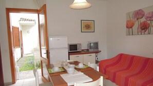 A compact living space with a dining area, kitchenette, and a sofa.
