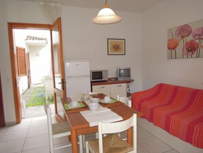 Ett kompakt bostadsutrymme med ett matbord, ett litet kök, en tv och en soffa.