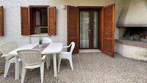 A patio with a table and chairs, a wooden door, and a fireplace.