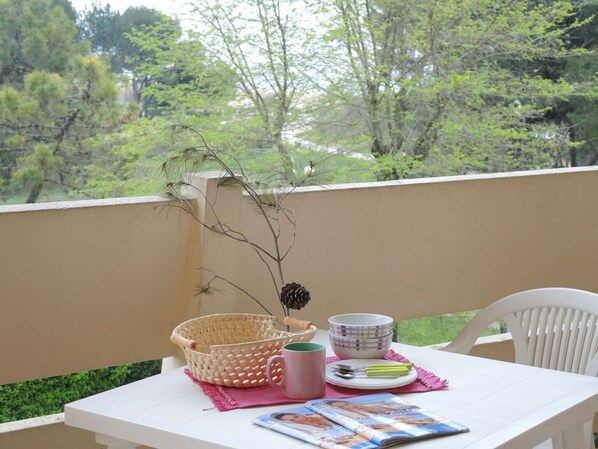 Un balcón con una mesa preparada para una comida, incluyendo una cesta, una taza y cuencos.