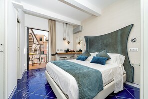 A bedroom with a bed, a desk, and a view of an outdoor area.