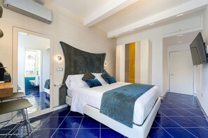 Una habitación de hotel moderna con una cama grande, un escritorio y un baño visible a través de una puerta de cristal.