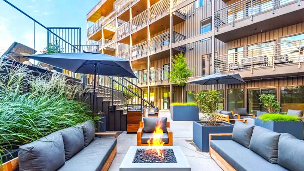 An outdoor seating area with sofas, a fire pit, and umbrellas. - ~Walk to Broadway & the Gulch~ King Bed, Balcony, Free Parking, Gym, Pool! (Nashville)
