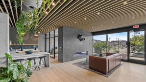 A modern lobby with a wooden ceiling, a seating area, and a view of the city through large windows. - ~Walk to Broadway & the Gulch~ King Bed, Balcony, Free Parking, Gym, Pool! (Nashville)