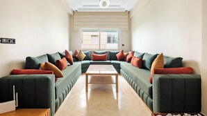 Een moderne woonkamer met een hoekbank, een houten salontafel en een kroonluchter.