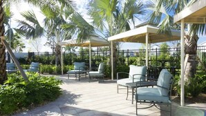 An outdoor patio area with seating under pergolas, surrounded by palm trees and a tiled floor. - Brand new Fantastic Home at Storey Lake (Kissimmee)