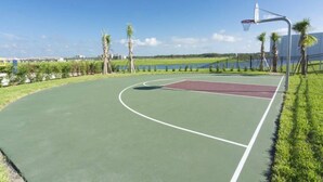 An outdoor basketball court with a green surface, a red center circle, and a metal basketball hoop. - Brand new Fantastic Home at Storey Lake (Kissimmee)