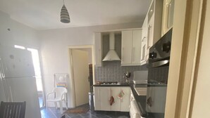 Una cocina funcional con armarios blancos, una estufa y una lámpara colgante.