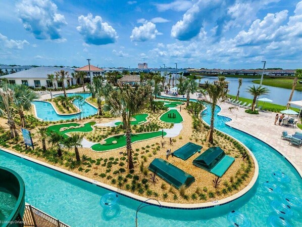 A resort pool area with multiple swimming pools, palm trees, and lounge chairs. - Enchanting Decor Home With Private Pool (Kissimmee)