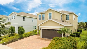 A residential area with two houses, each with a garage and surrounded by well-maintained gardens. - Charming Home With Private Pool at Encore Resort (Kissimmee)