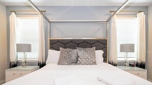 A modern hotel room with a large bed, two nightstands, a headboard, and curtains. - Charming Home With Private Pool at Encore Resort (Kissimmee)