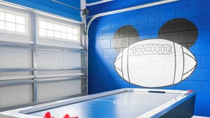 A pool table in a room with blue walls and a mural of a football. - Charming Home With Private Pool at Encore Resort (Kissimmee)