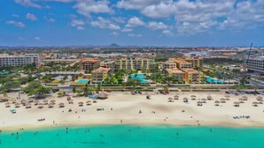A beach resort with multiple buildings, a sandy beach, and clear turquoise waters.