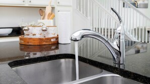 A kitchen with a stainless steel sink, a modern faucet, and a wooden spice rack. - Beautiful Townhome W/pool Close to Disney (Davenport)
