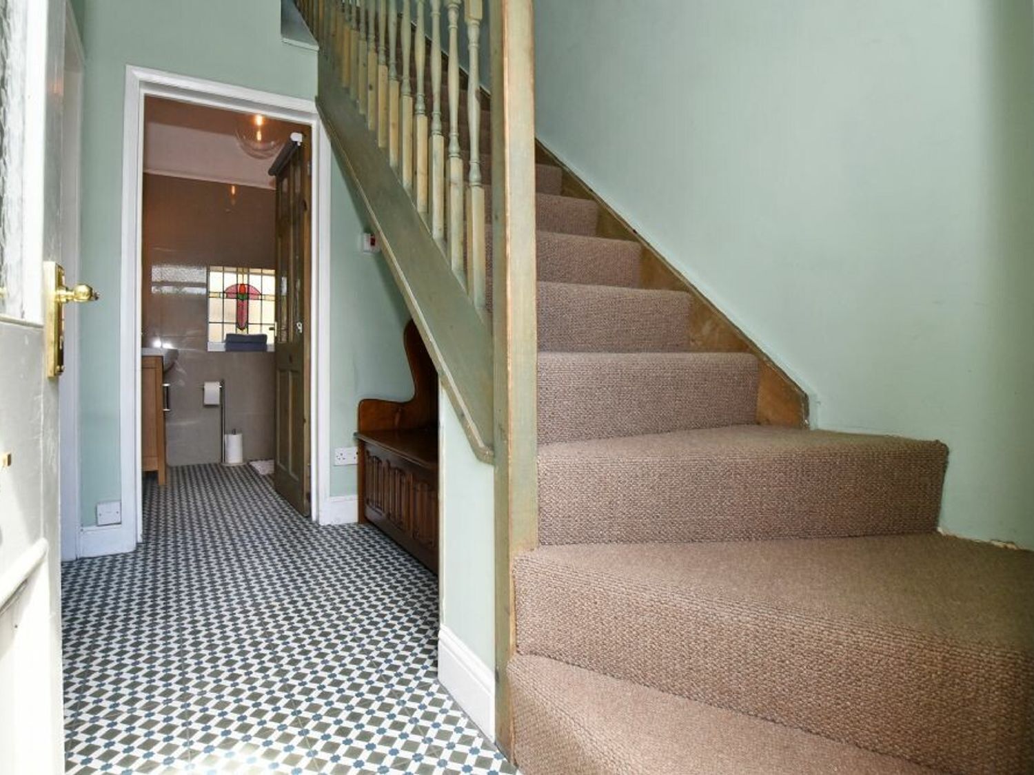 Un escalier dont les marches sont recouvertes de moquette, menant à un palier.
