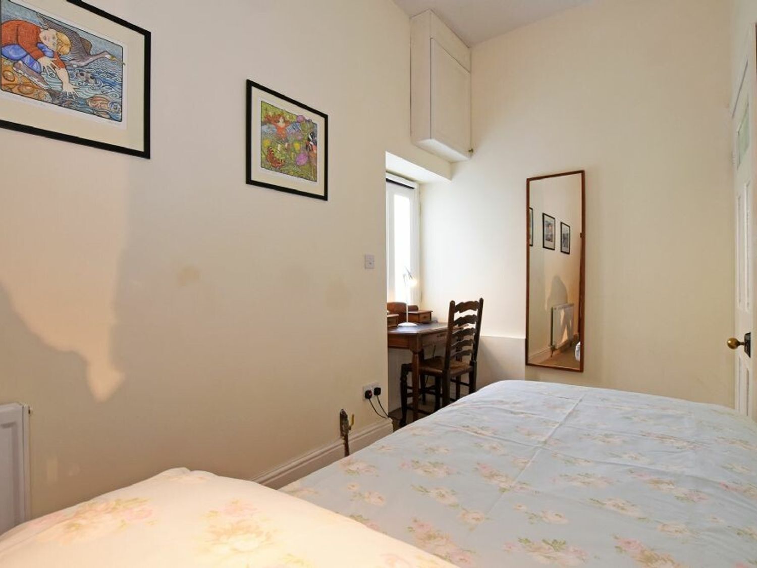 A bedroom with a bed, a chair, a desk, and a mirror.