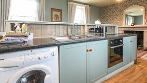 A compact kitchen with a washing machine, a coffee maker, and a microwave.